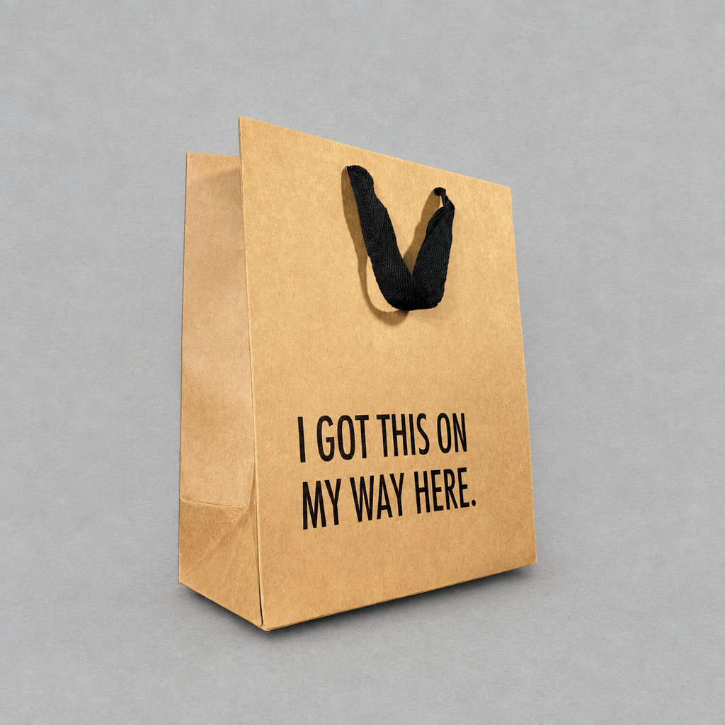 Impish Greetings kraft paper gift bag with black cloth handles and the text I Got This on my Way Here printed on it.