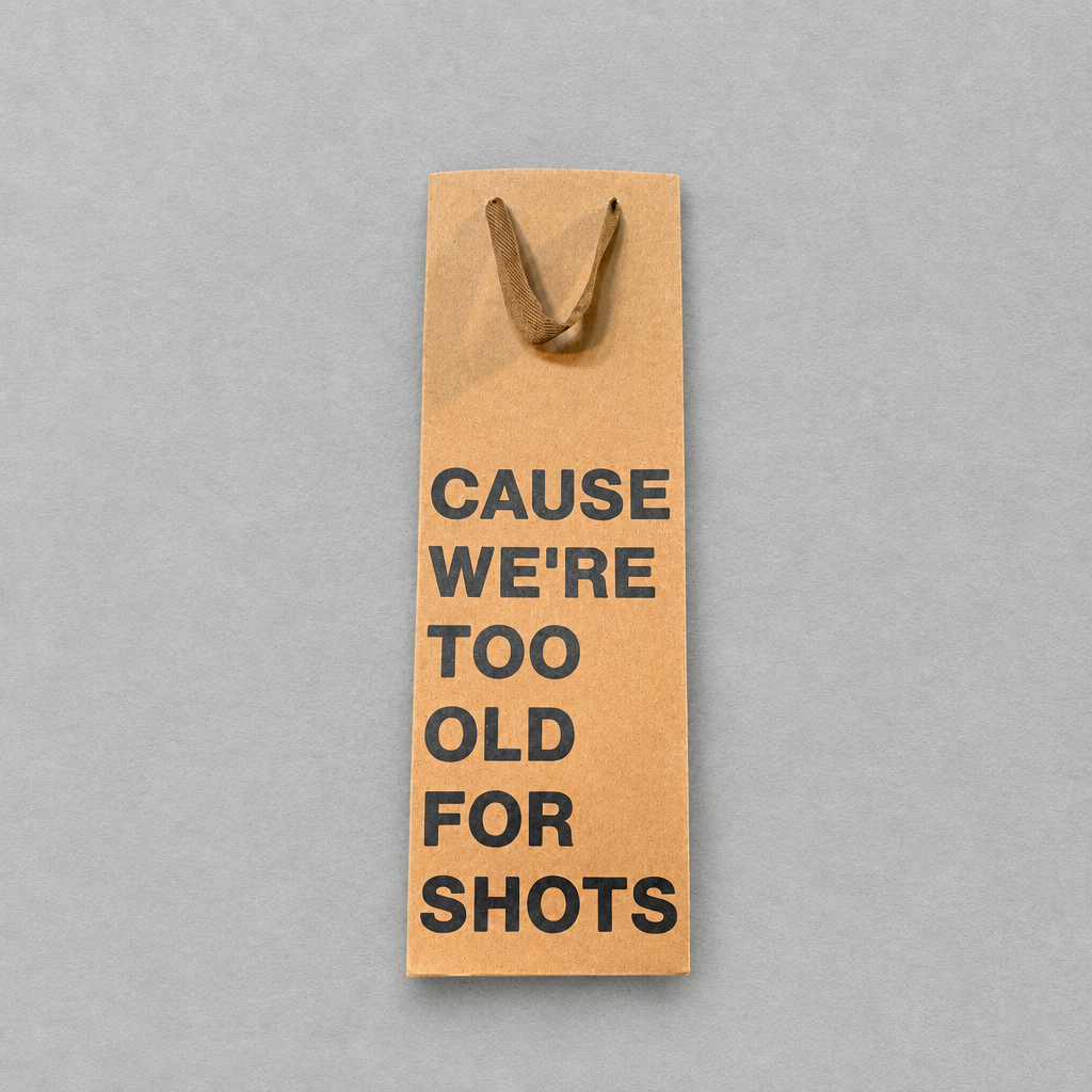 Impish Greetings kraft paper wine gift bag with black text reading Cause We're Too Old For Shots