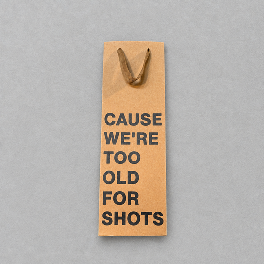Impish Greetings kraft paper wine gift bag with black text reading Cause We're Too Old For Shots