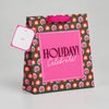 Impish Greetings large gift bag with green floral pattern, pink Holiday Celebrate label, and metallic ribbon handle.