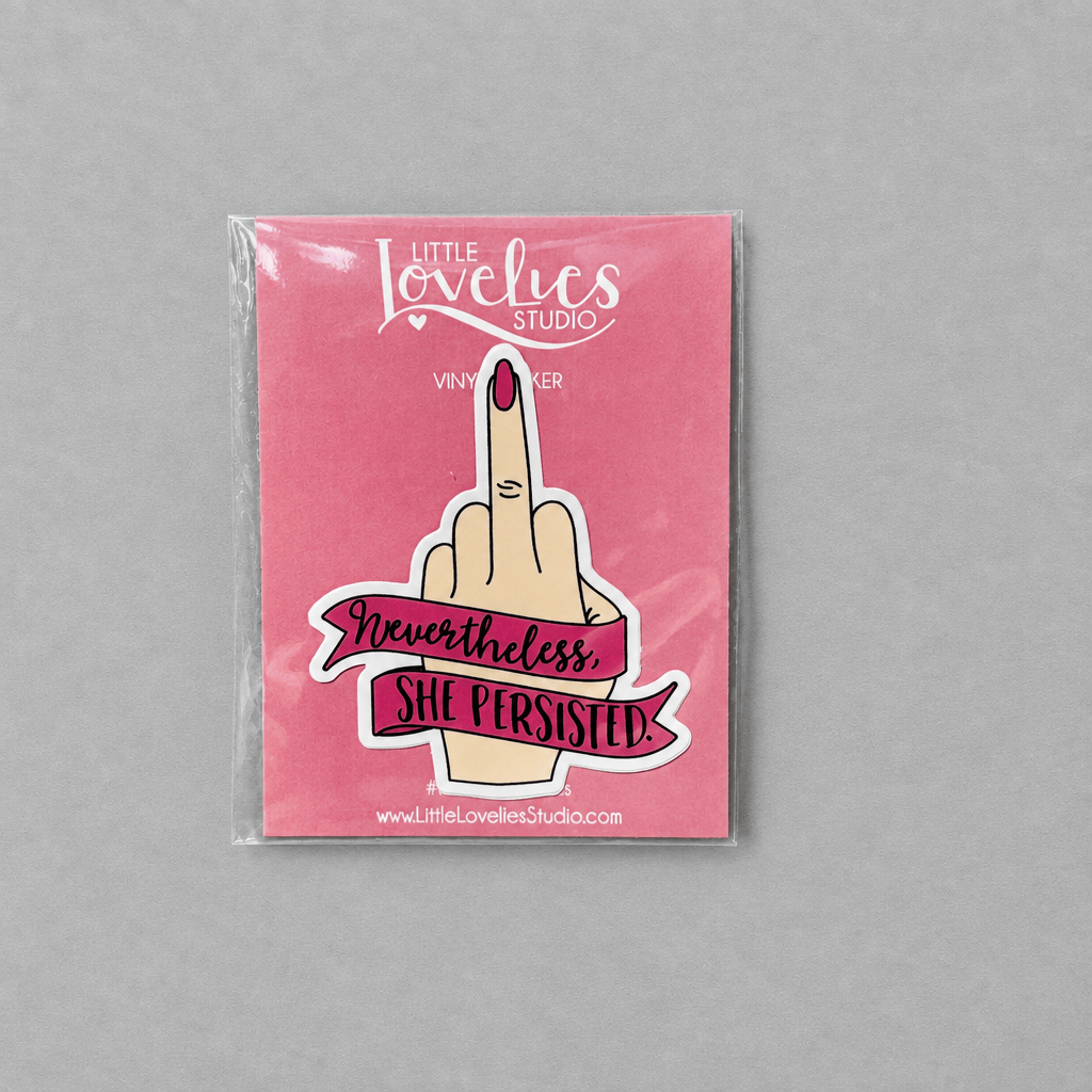 Impish Greetings Nevertheless She Persisted vinyl sticker featuring a hand giving the middle finger on a pink card