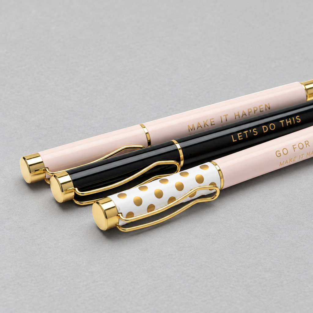 Impish Greetings set of three motivational metal ballpoint pens in light pink, black, and white with gold accents.