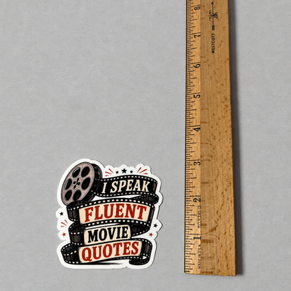 Impish Greetings I Speak Fluent Movie Quotes sticker with film reel design next to a wooden ruler for scale