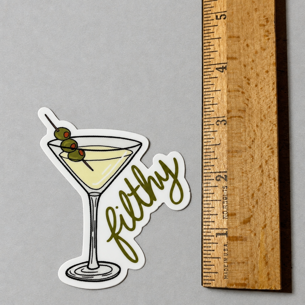 Impish Greetings Filthy Dirty Olive Martini sticker featuring a cocktail glass with three olives on a wooden ruler