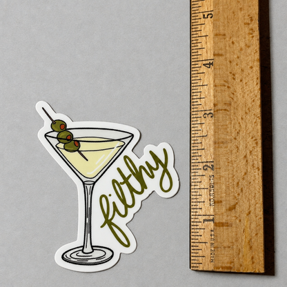 Impish Greetings Filthy Dirty Olive Martini sticker featuring a cocktail glass with three olives on a wooden ruler