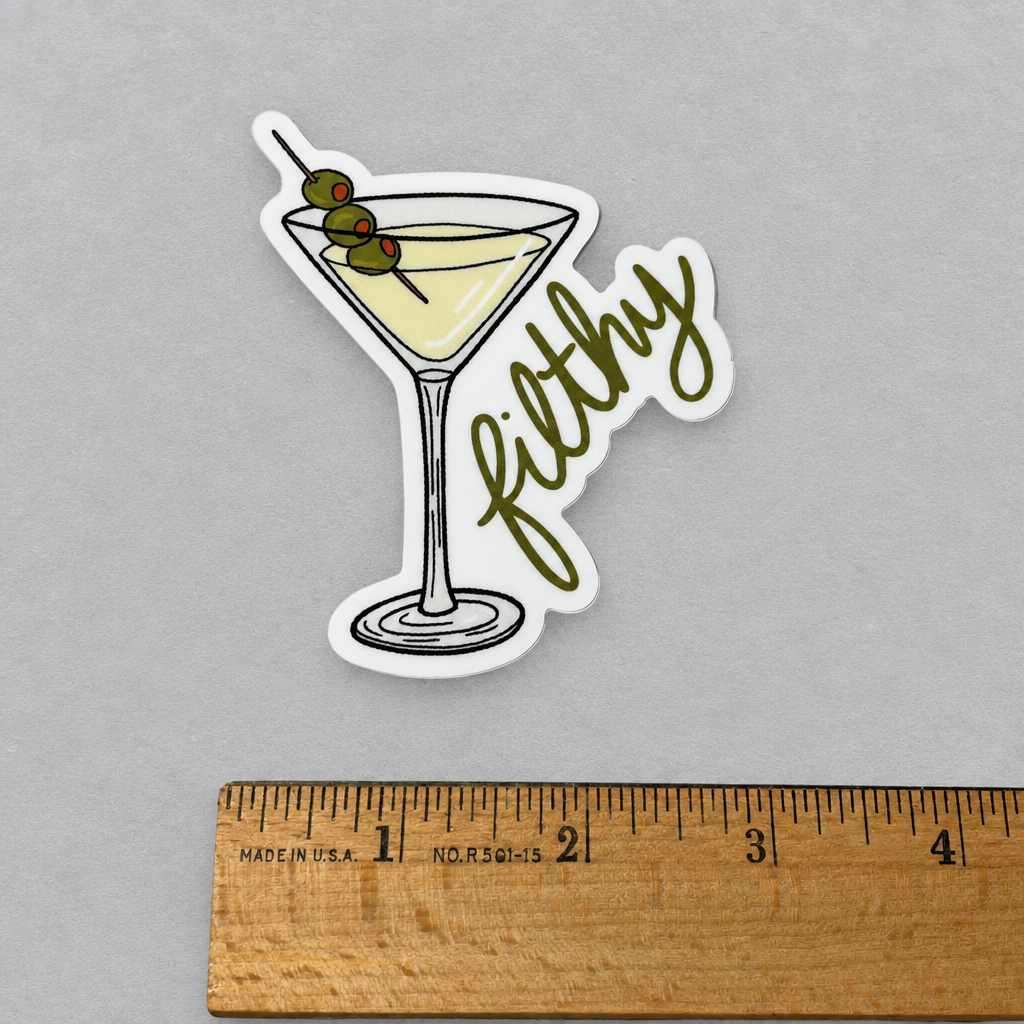 Impish Greetings Filthy Dirty Olive Martini sticker featuring a cocktail glass with three olives on a wooden ruler.
