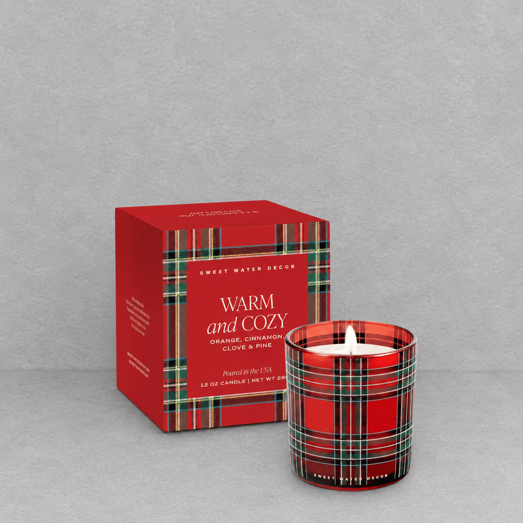 Impish Greetings Warm and Cozy soy candle in a red plaid glass jar with matching gift box on a grey background.