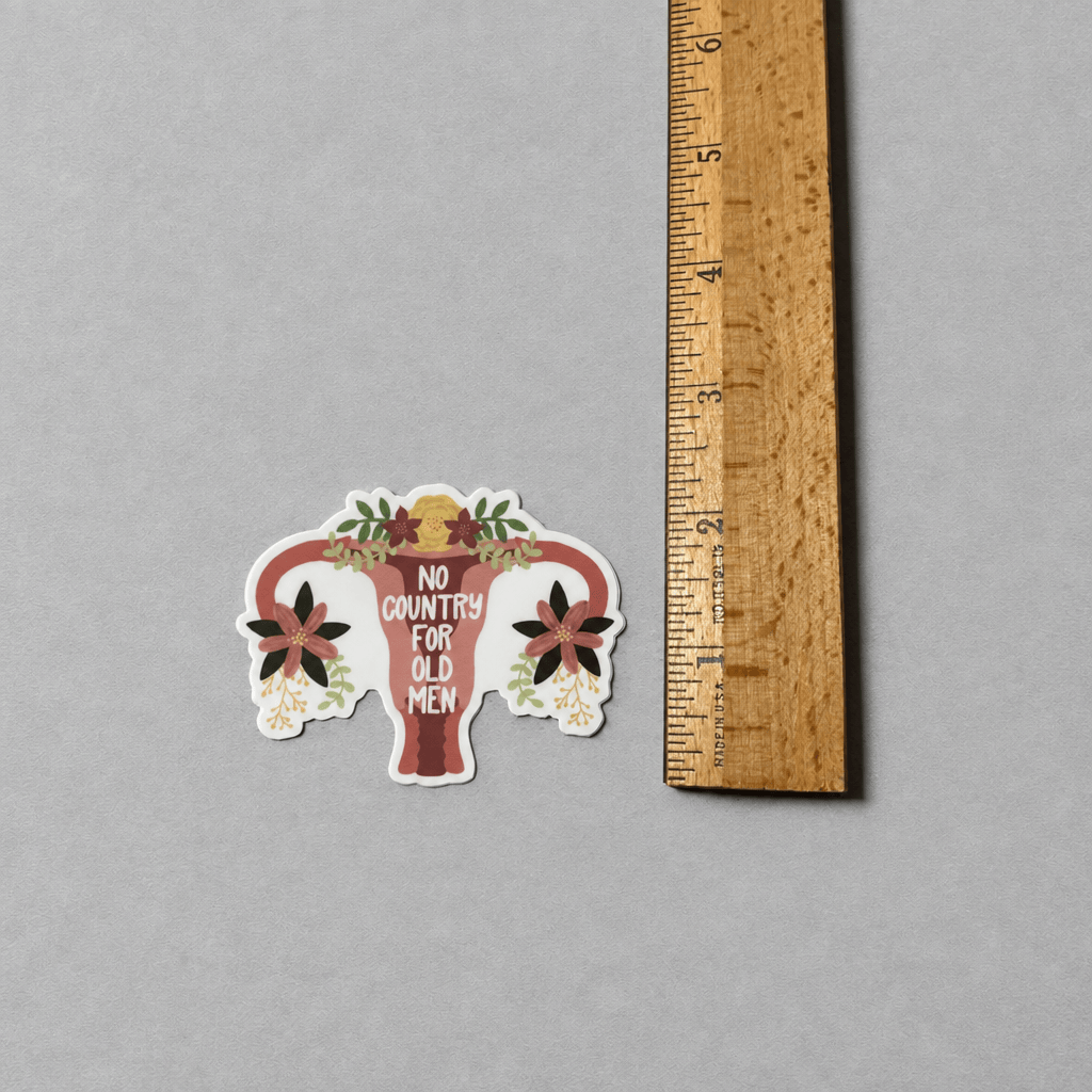 Impish Greetings No Country For Old Men pro-choice vinyl sticker with floral uterus design next to a wooden ruler.