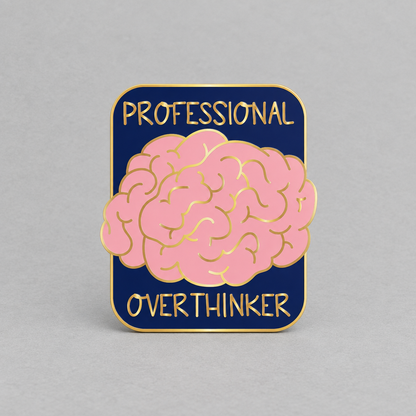 Impish Greetings Professional Over-thinker enamel pin with a pink brain design on a navy background and gold plating.
