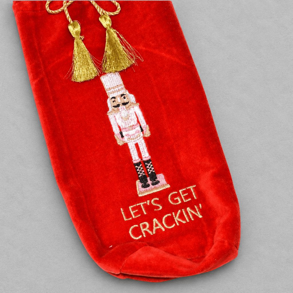 Impish Greetings red velvet wine gift bag featuring nutcracker embroidery and gold tassel closure