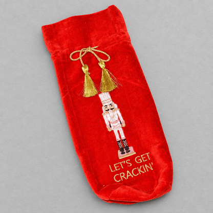 Impish Greetings red velvet wine gift bag featuring nutcracker embroidery and gold tassel drawstring closure