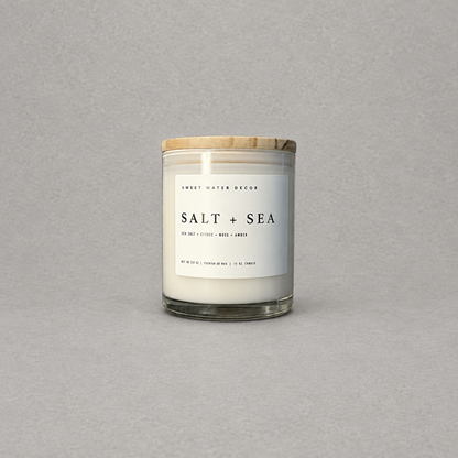 Impish Greetings Salt and Sea 11 oz soy candle in a glass jar with a wooden lid against a grey background.