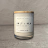 Impish Greetings 11 oz Salt and Sea soy candle in a glass jar with a wooden lid on a wooden surface