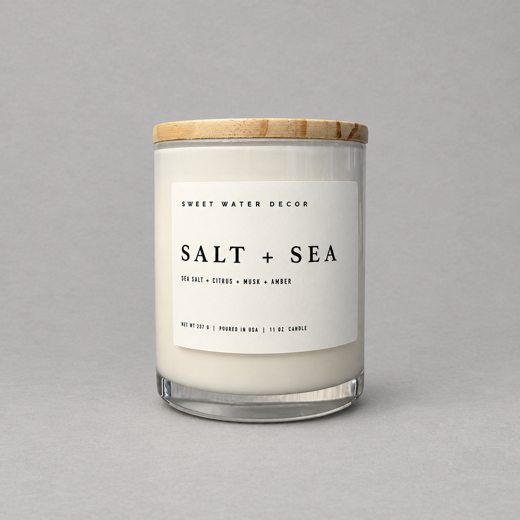 Impish Greetings Salt and Sea 11 oz soy candle in a glass jar with a wooden lid against a grey background