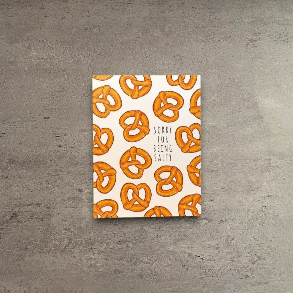 Impish Greetings Sorry for Being Salty apology card featuring a pattern of golden brown pretzels on a cream background