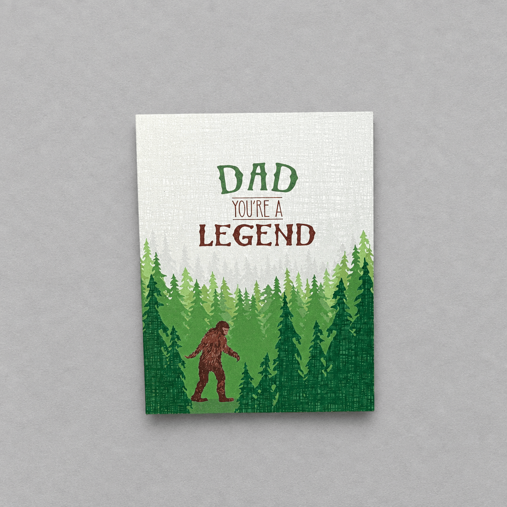 Impish Greetings Sasquatch Legend Dad card featuring a Bigfoot illustration in a forest with text Dad You're a Legend