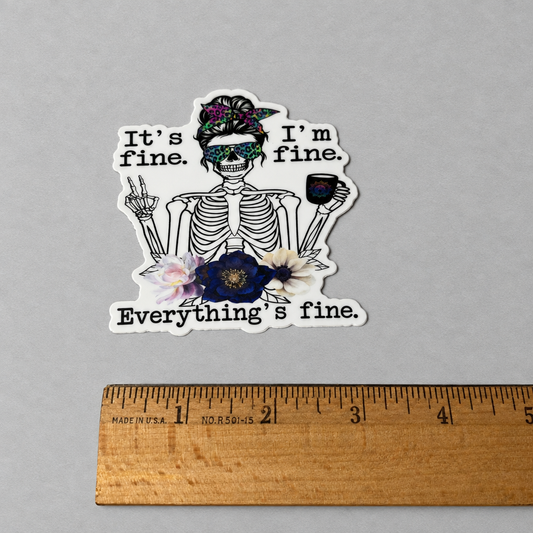 Impish Greetings vinyl sticker featuring a skeleton with a floral headband, sunglasses, and coffee, text says It's fine