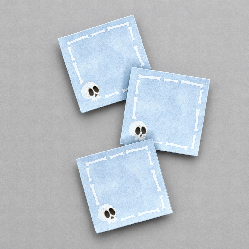 Impish Greetings light blue square Post-it notes featuring a white skull and bone border design on a grey background.