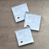 Impish Greetings Skull & Bones Post-it Notes with a light blue background and white bone border on a wooden surface.