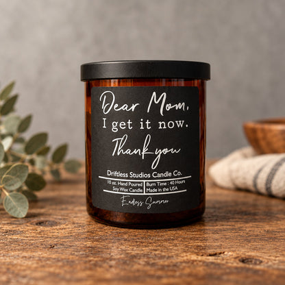 Impish Greetings Dear Mom I Get It Now soy wax candle in an amber glass jar with a black lid and Endless Summer scent
