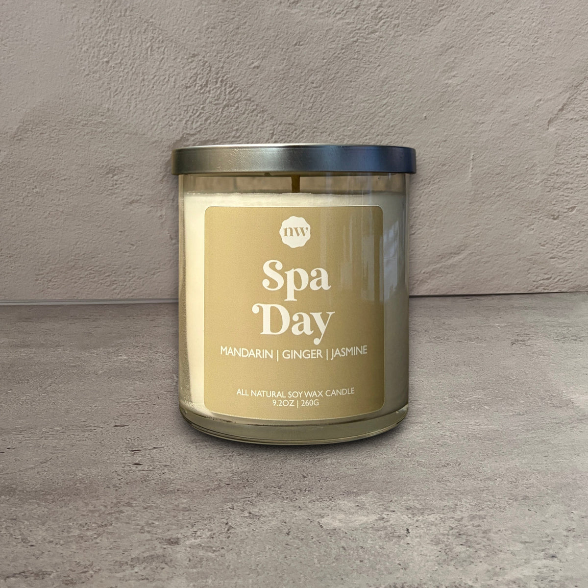 Impish Greetings Spa Day soy wax candle in a glass jar with a silver lid, featuring mandarin, ginger, and jasmine.