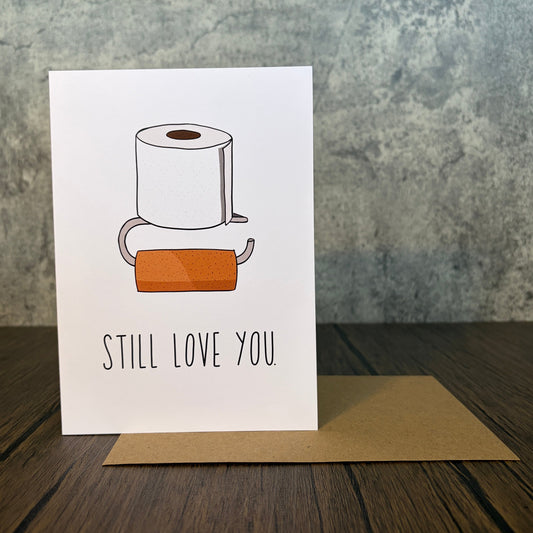 Still Love You card featuring a toilet paper roll illustration on white matte card stock with envelope
