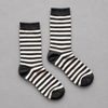Impish Greetings black and white striped organic cotton crew socks with scalloped edges on a grey background