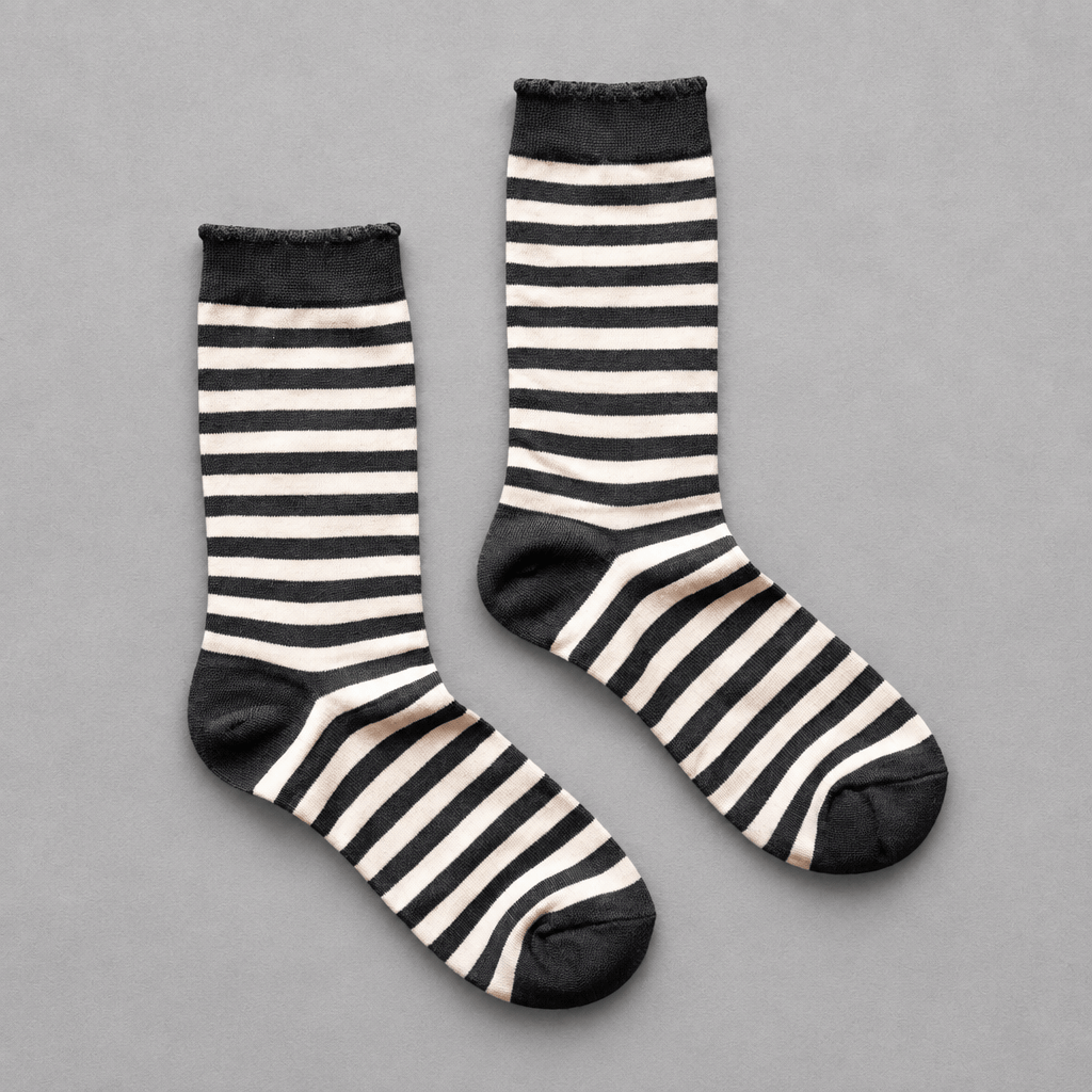 Impish Greetings black and white striped organic cotton crew socks with scalloped edges on a grey background