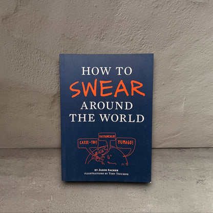 Impish Greetings How to Swear Around the World paperback book with a dark blue cover and orange text.