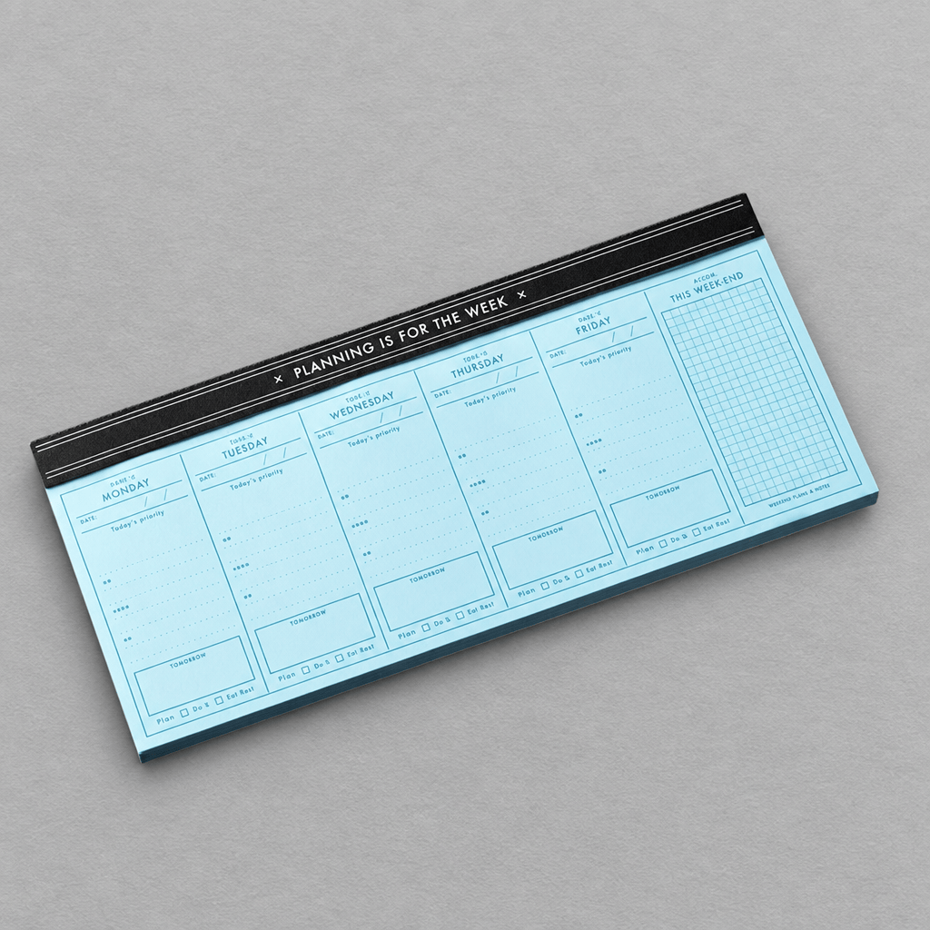 Impish Greetings Planning Is For The Week notepad with light blue pages and black binding on a grey background.