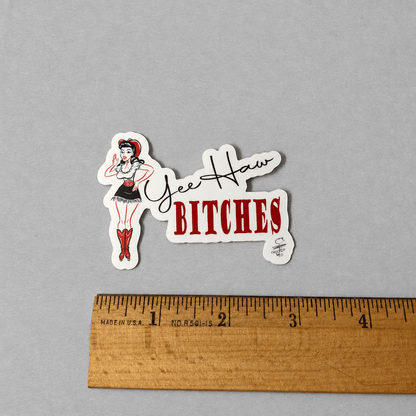 Impish Greetings Yee Haw Bitches vinyl sticker featuring a pin-up cowgirl illustration on a grey background.
