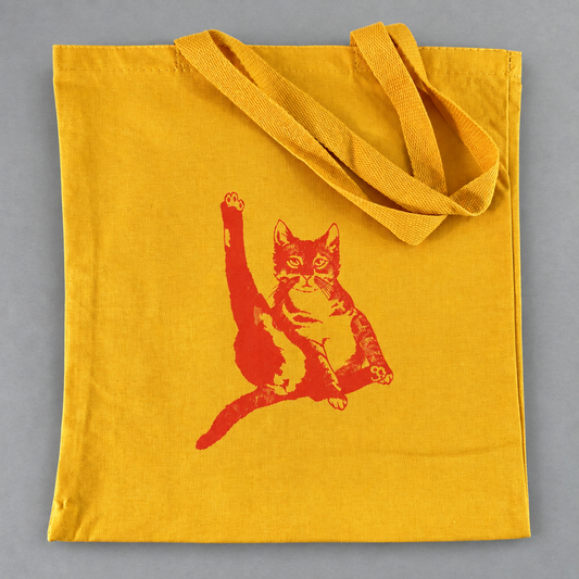 Impish Greetings yellow canvas tote bag featuring a red illustrated cat graphic