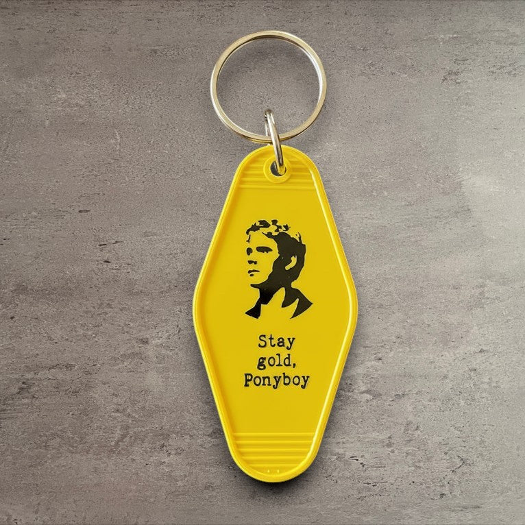 Impish Greetings yellow vintage-style motel key fob featuring a Ponyboy illustration and Stay gold Ponyboy text.