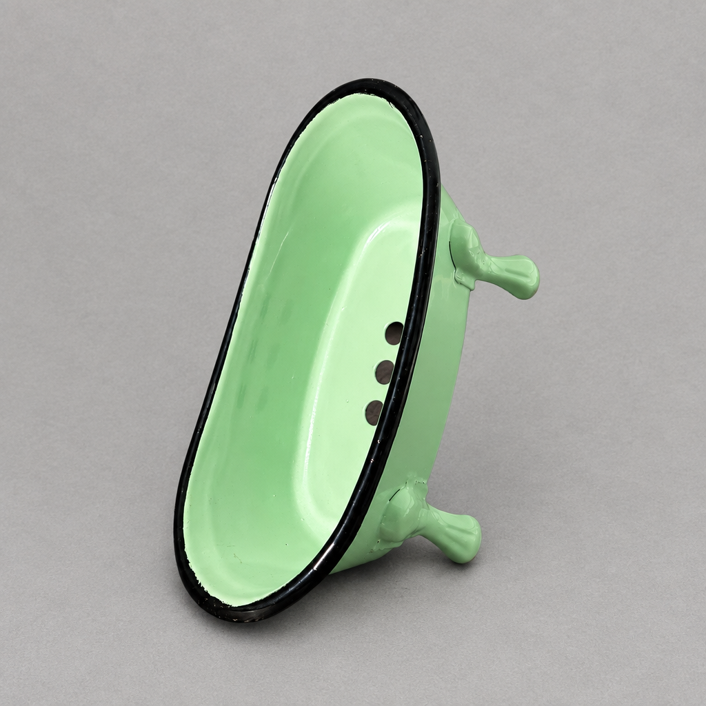 A mint green antique clawfoot soap holder with a green inside against a grey background