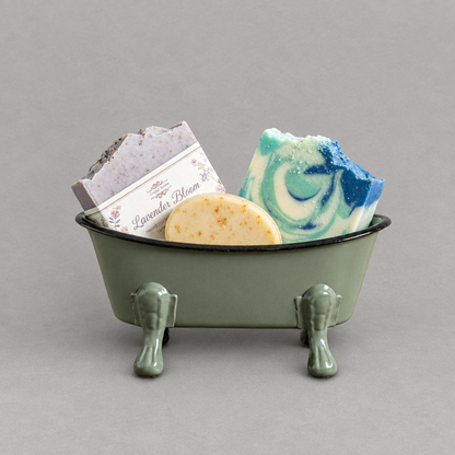 A green antique clawfoot soap holder with a green inside holding three colorful soap against a grey background
