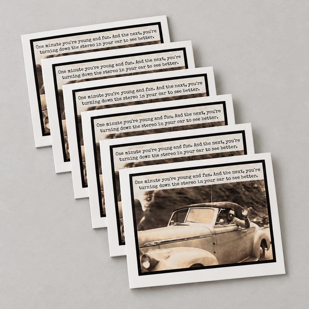 A set of printed cards or booklets fanned out on a textured gray concrete surface. Each card has a black-and-white photo of a car at the bottom and a block of text above it.